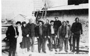 Mitarbeiter und Rentner vor dem Betriebsgebäude der Papierfabrik Lang. An die Fahne wurde ein Trauerflor gehängt.