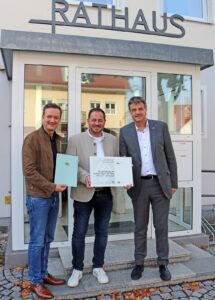 Der Leiter des Amt für Ländliche Entwicklung Schwaben, Christian Kreye (rechts) übergab am Montagnachmittag im Beisein des Landtagsabgeordneten Peter Wachler (links) den Förderbescheid für die Neugestaltung der Außenanlage am alten Siebnacher Pfarrhof an Bürgermeister Roland Wagner (Mitte). Foto: Marcus Barnstorf/Unterallgäu Rundschau        